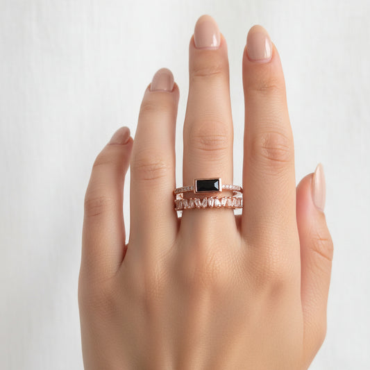 Rose gold ring with black gemstone on a beige cushion in a jewelry box