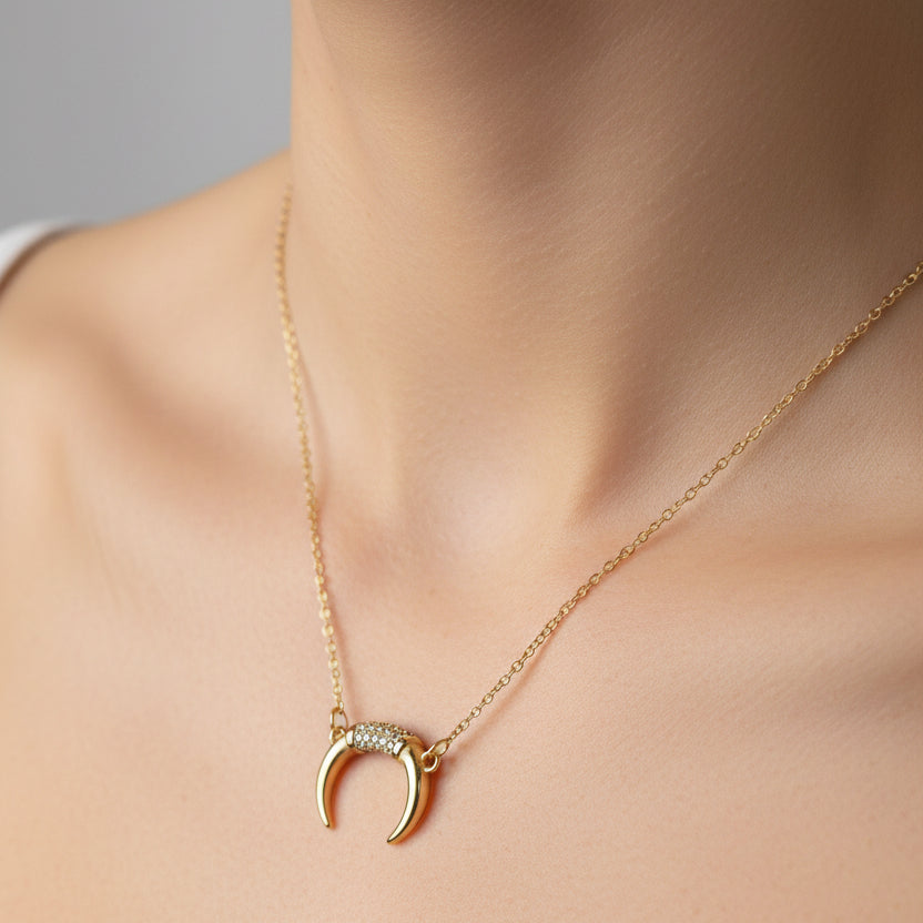 Gold necklace with a crescent moon pendant on a white surface