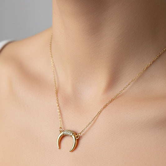 Gold necklace with a crescent moon pendant on a white surface