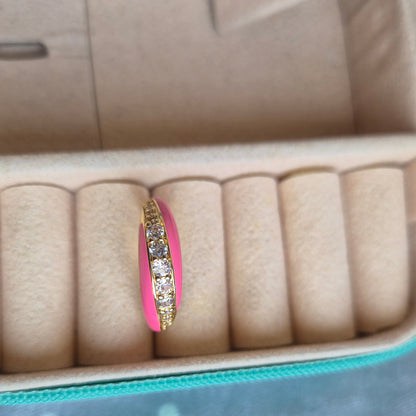 Pink ring with gold band and diamond accents on a jewelry case.